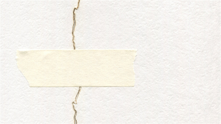 torn piece of paper held together by a patch